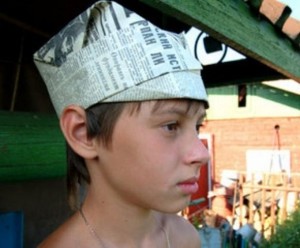 Мальчик с газетной шляпой с козырьком